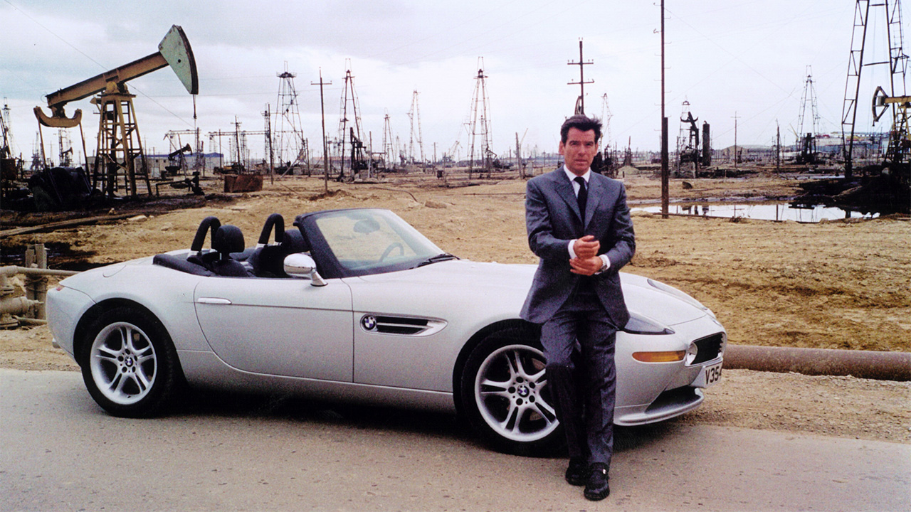 Pierce Brosnan leaning on a silver BMW Z8 with the roof down