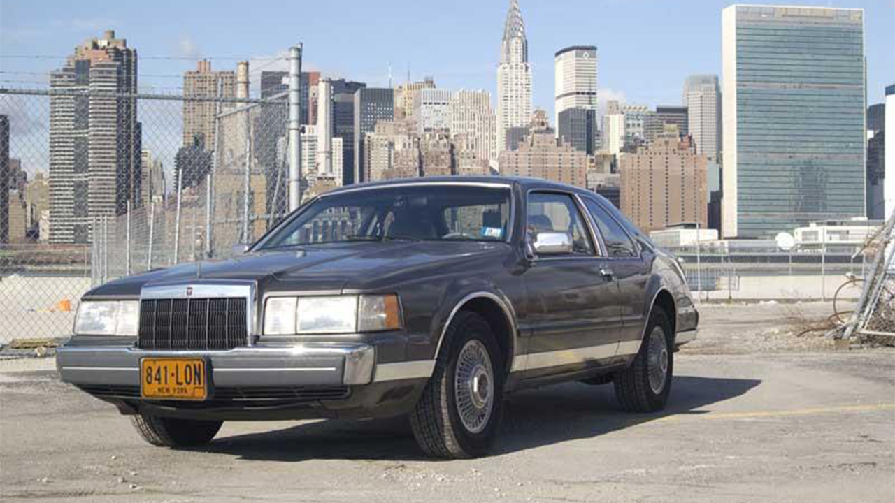 Lincoln Continental parked in front of city backdrop