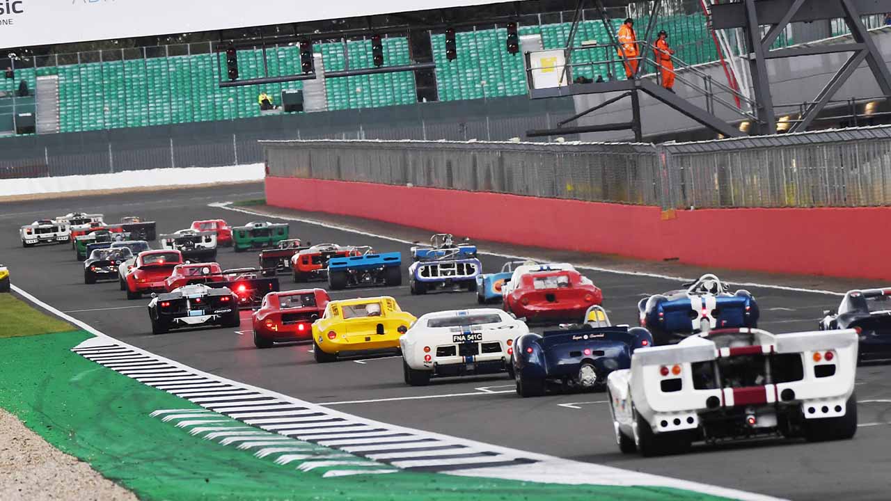 Historic cars racing down one of the straights at Silverstone