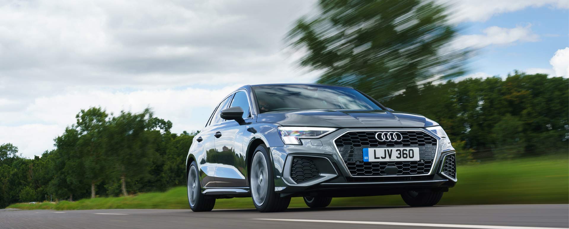 Grey Audi A3 Sportback rolling shot, driving down a country road
