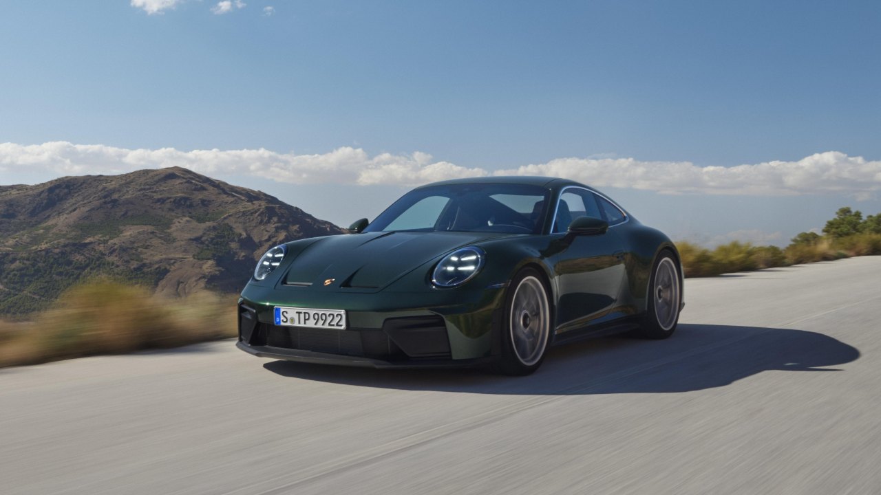 Green Porsche 911 GT3 Touring driving along a mountain road