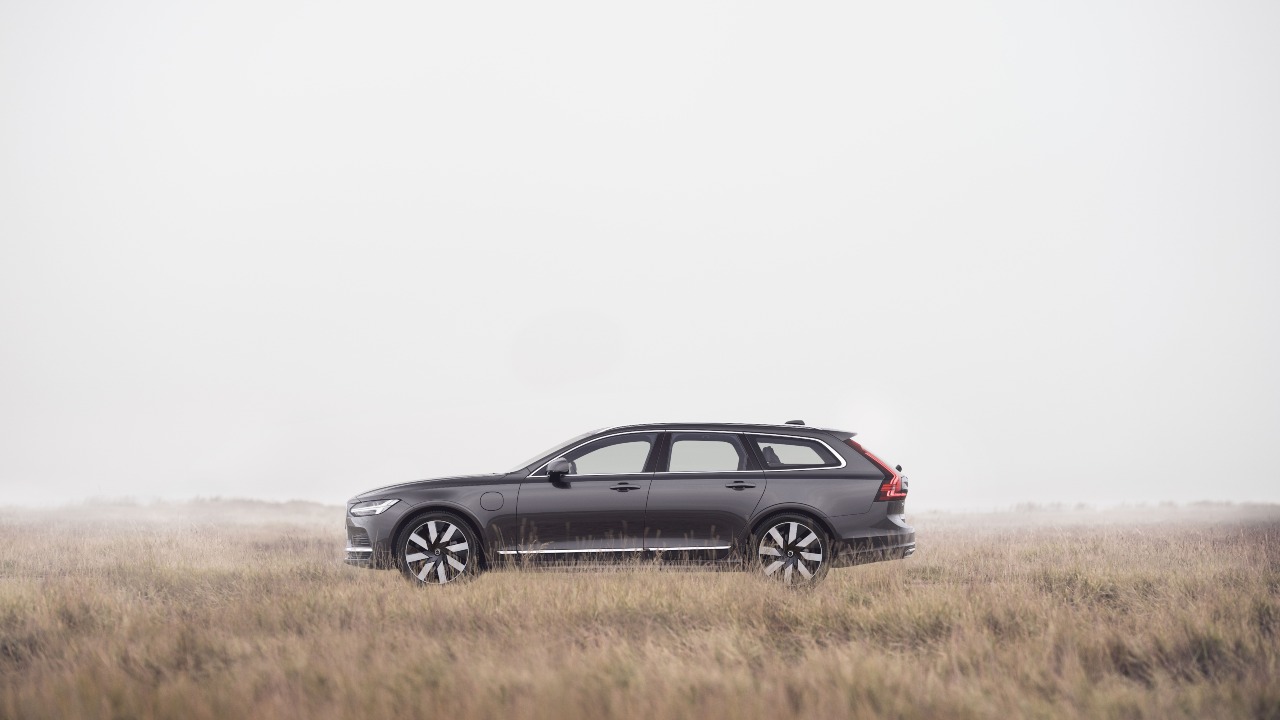 Dark grey Volvo V90 parked in a misty field, side profile