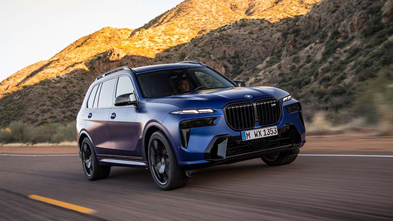 BMW X7 luxury SUV driving on a desert road surrounded by rocky mountain scenery