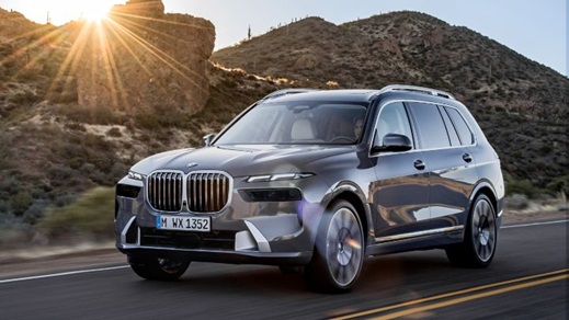 BMW X7 luxury SUV driving at sunset on an open road through rugged desert terrain