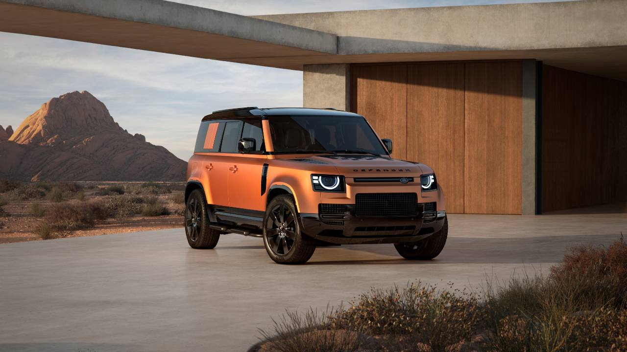 Land Rover Defender 110 parked outside a contemporary desert home with rugged mountain backdrop