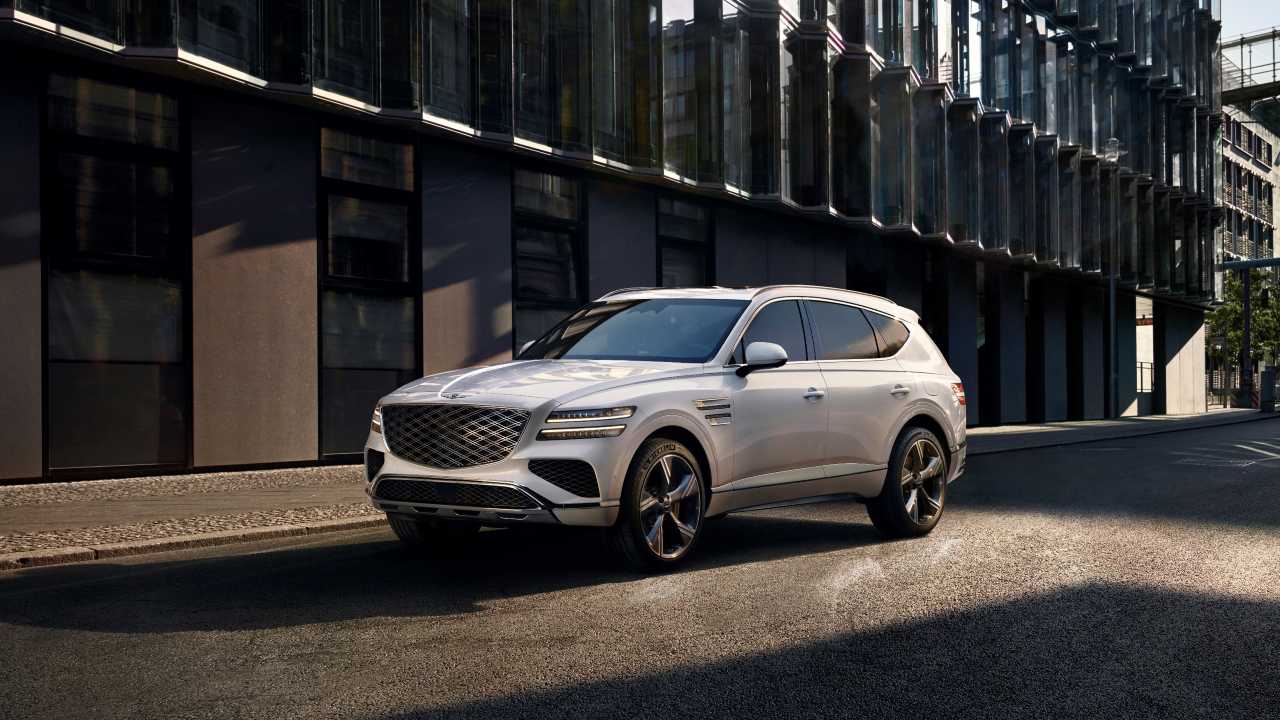 Genesis GV90 luxury SUV driving through a modern city street environment