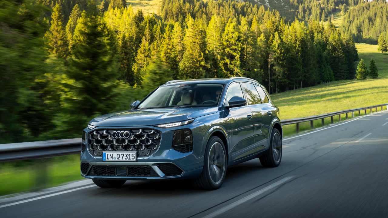 Audi Q7 large SUV driving on a scenic forest road surrounded by greenery