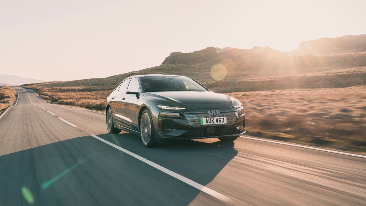 Audi A6 e-tron driving through a sunlit rural landscape