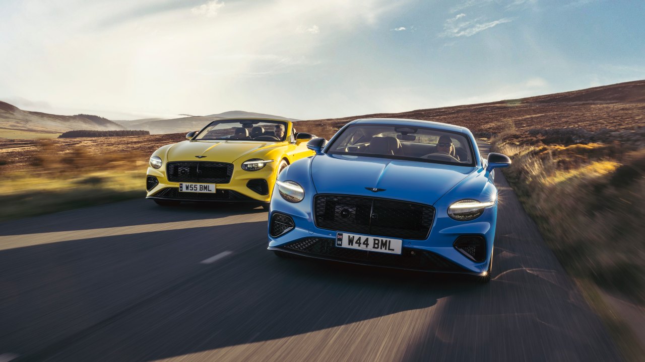 Two Bentley Continental GT grand tourers driving on an open road from a front three‑quarter angle