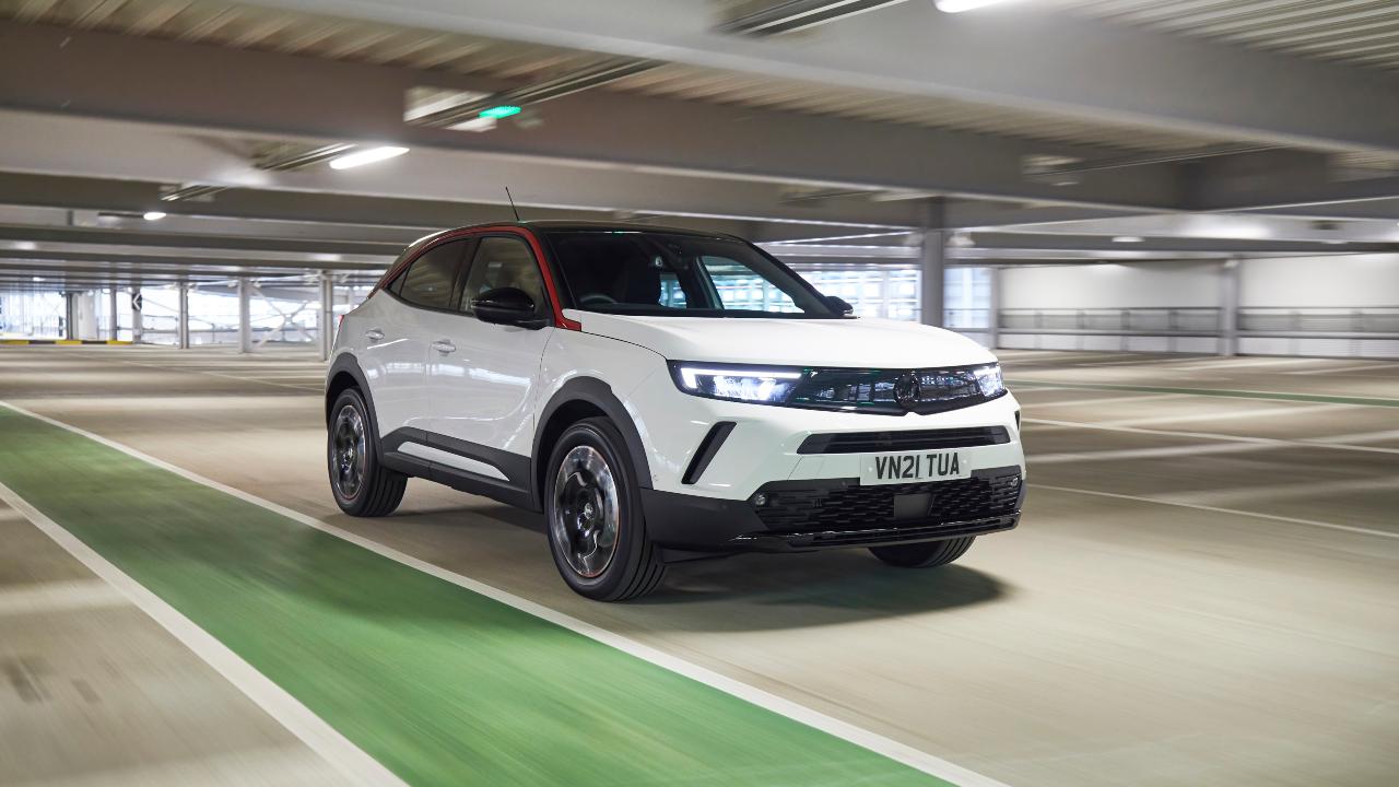 White Vauxhall Mokka driving through a multi‑storey car park from a front three‑quarter angle