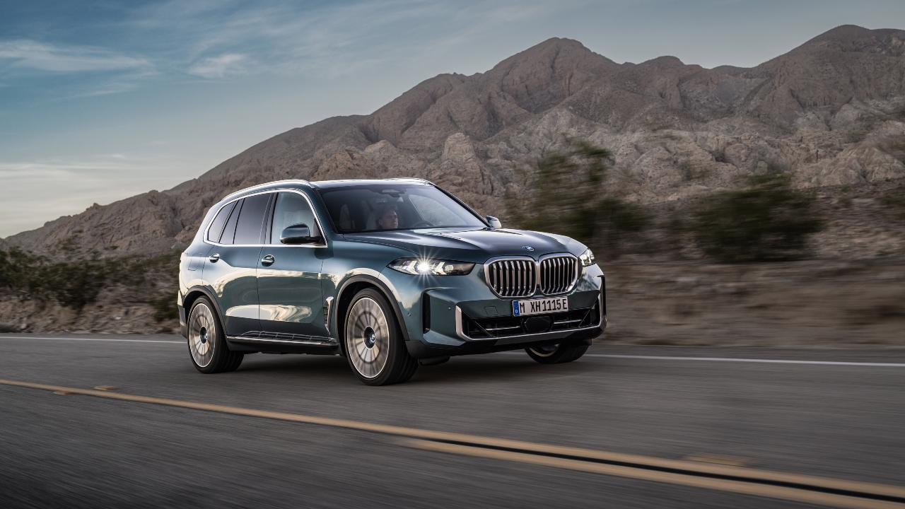 BMW X5 driving on scenic mountain road with rugged landscape