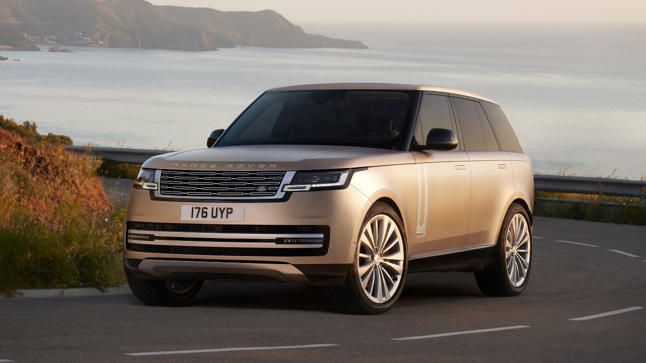 Range Rover driving on coastal road with ocean and cliffs in background