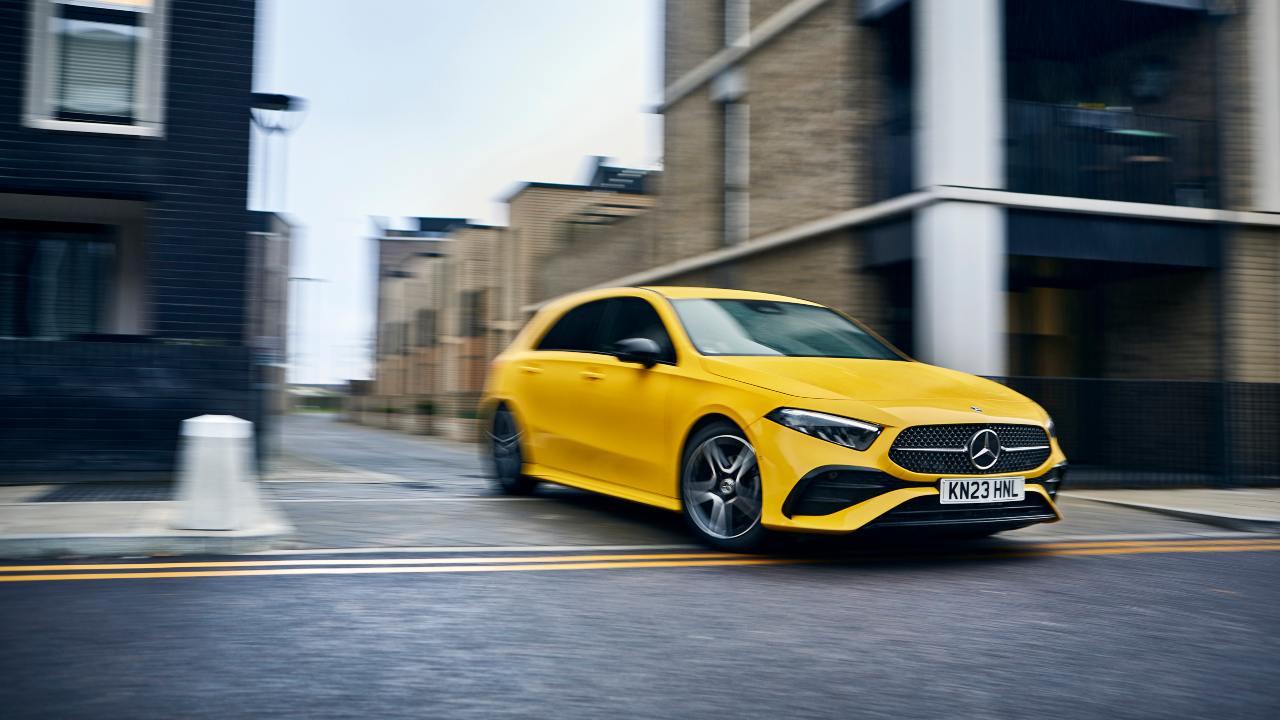Yellow Mercedes-Benz A-Class driving through urban streets with motion blur