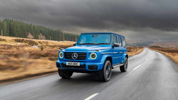 Blue Mercedes-Benz G-Class driving on rural road, front three-quarter view