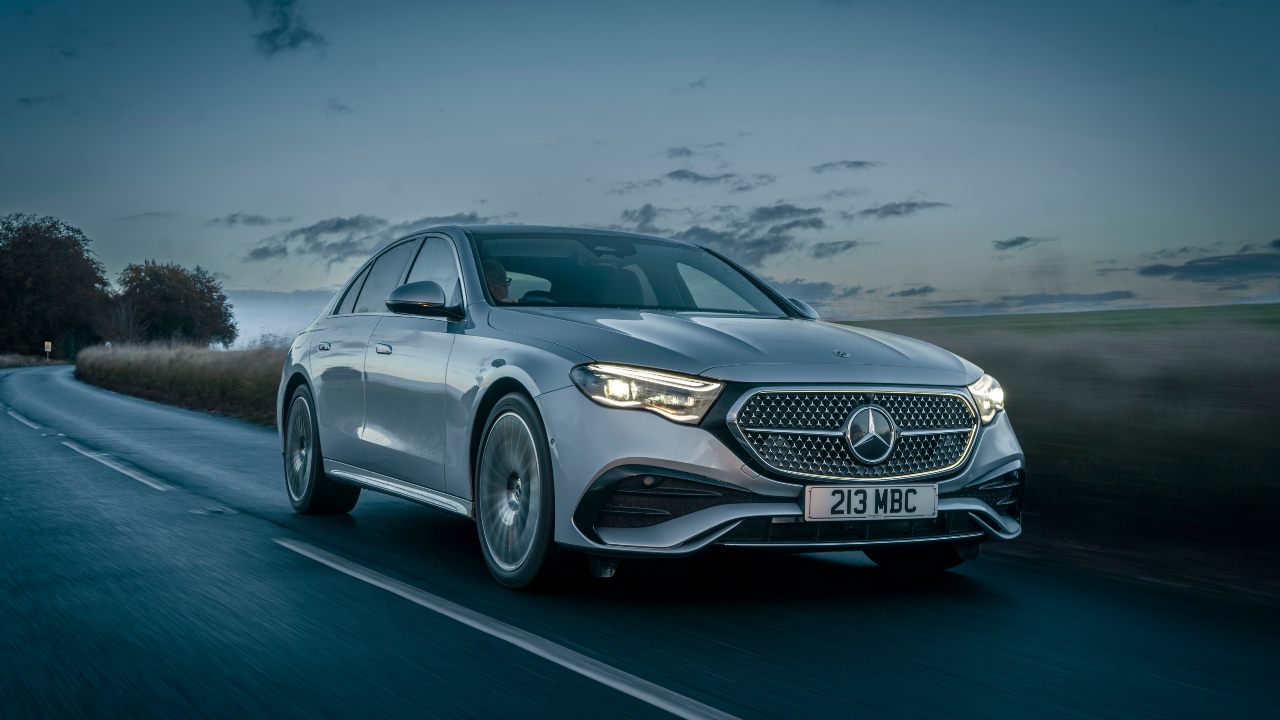 Silver Mercedes-Benz E-Class saloon driving on a country road at dusk