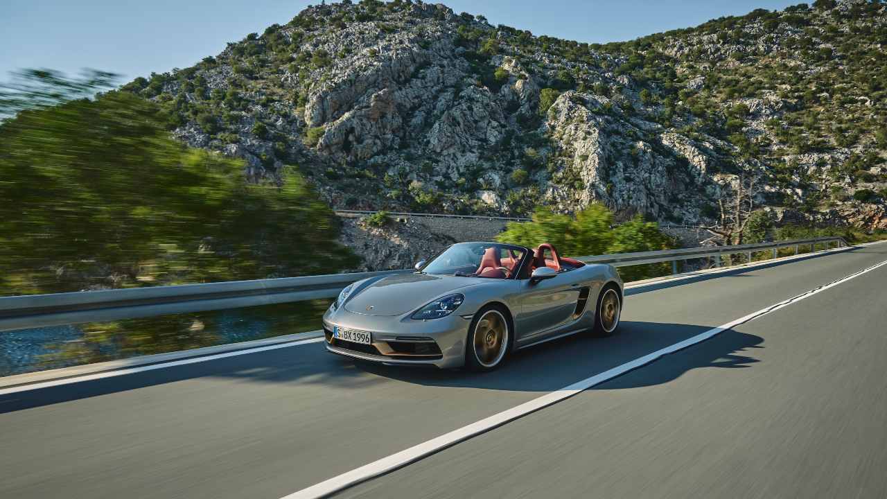 Green Porsche 718 Cayman driving with roof down