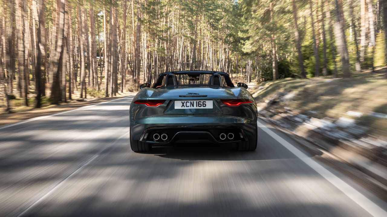Green Jaguar F-TYPE rear end driving with roof down