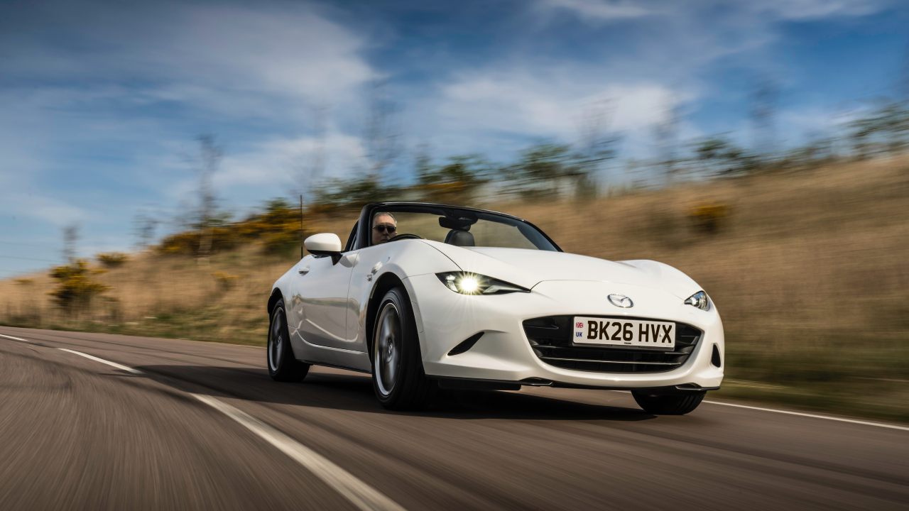 White Mazda MX-5 driving with roof down
