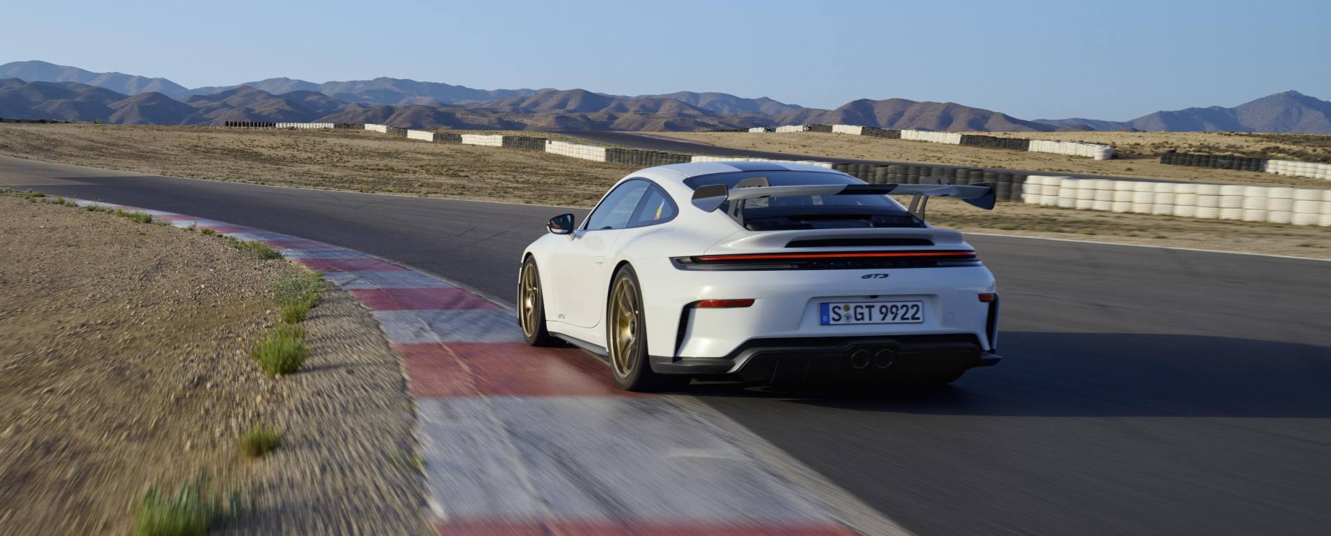Porsche 911 GT3 driving on race track rear left