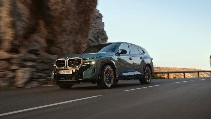BMW XM driving through mountain pass, front three-quarter view with motion blur
