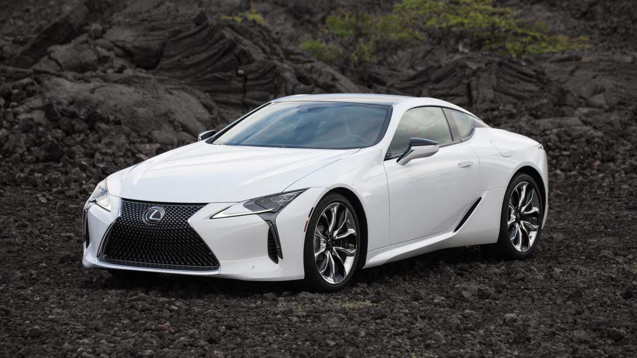 White Lexus LC coupe parked on volcanic landscape, front three-quarter view