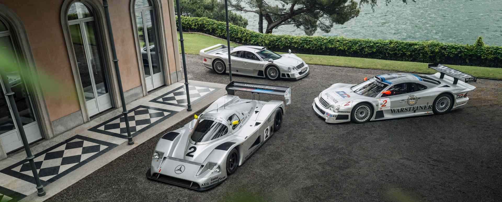 Mercedes-Benz CLK GTR, C11 race car and road car displayed outside lakeside villa