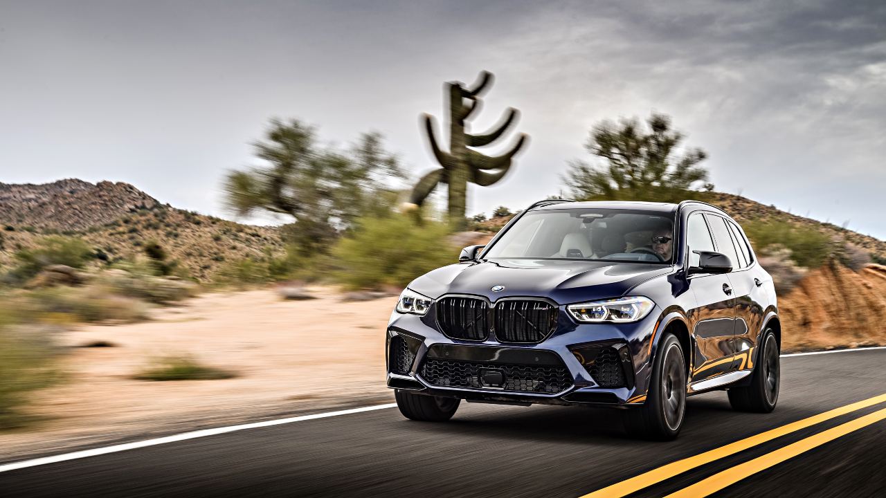 BMW X5 M Competition driving on a desert road with cacti in the background