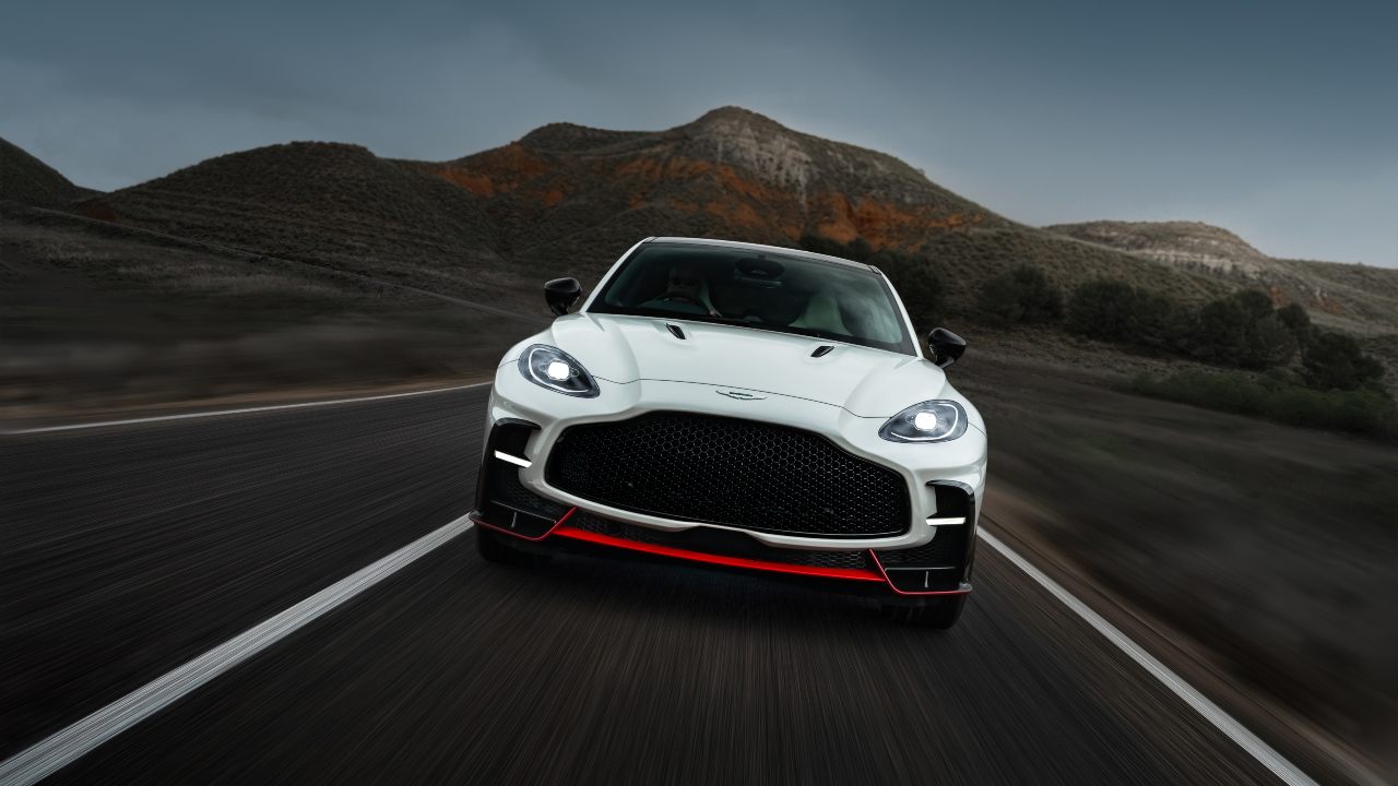Aston Martin DBX S driving at speed on a mountain road with blurred scenery