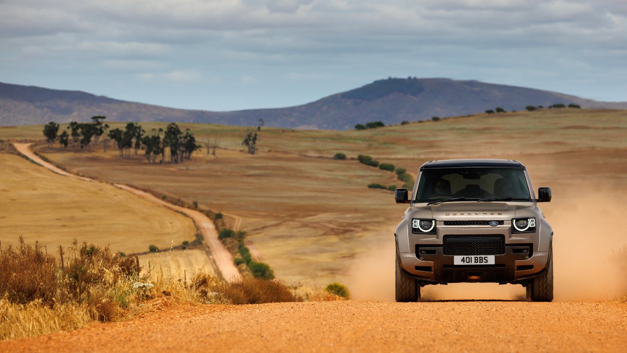 Land Rover Defender OCTA driving on a dusty off-road trail in open countryside