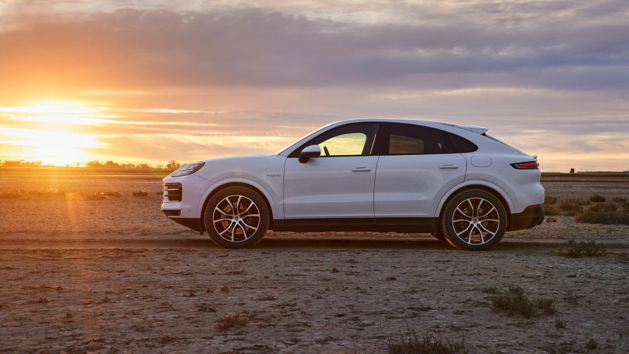 Porsche Cayenne E-Hybrid parked at sunset on a flat open landscape