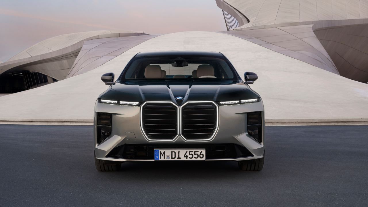 BMW 7 Series luxury saloon front view with illuminated kidney grille against a modern architectural backdrop