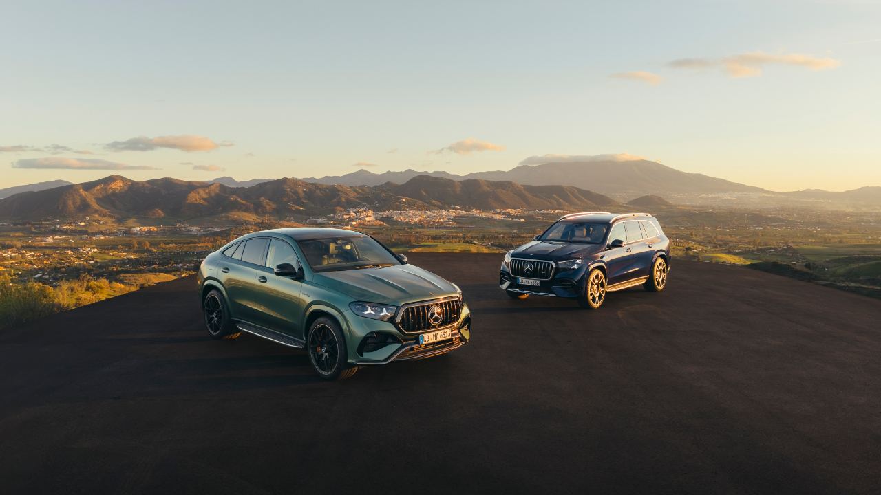 Mercedes-AMG SUV lineup parked on a hilltop at sunset with mountain scenery in the background