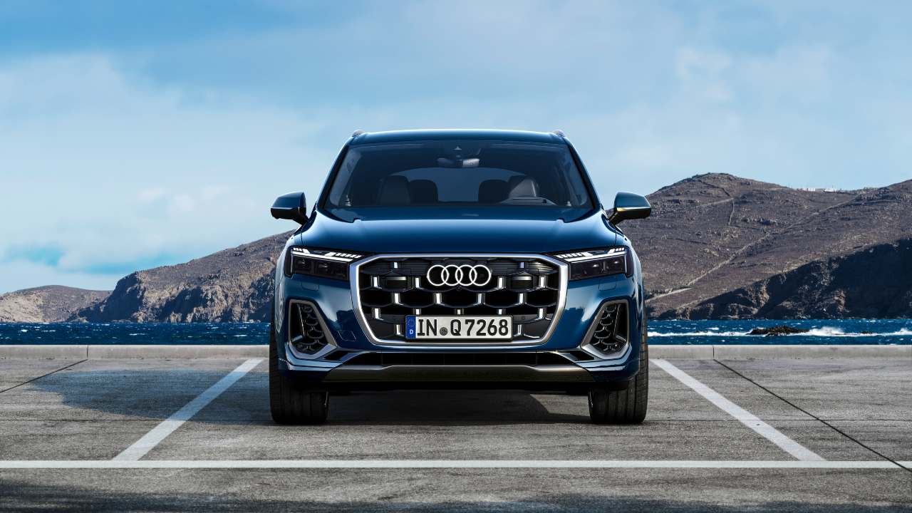 Audi Q5 SUV shown from the front, parked by the coast with mountains in the background