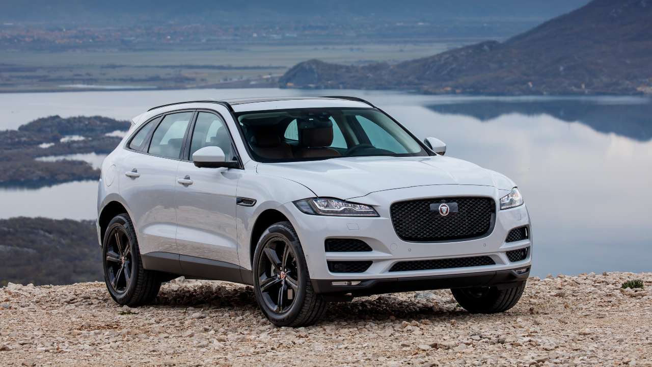 Jaguar F‑PACE SUV parked on rocky terrain overlooking a body of water