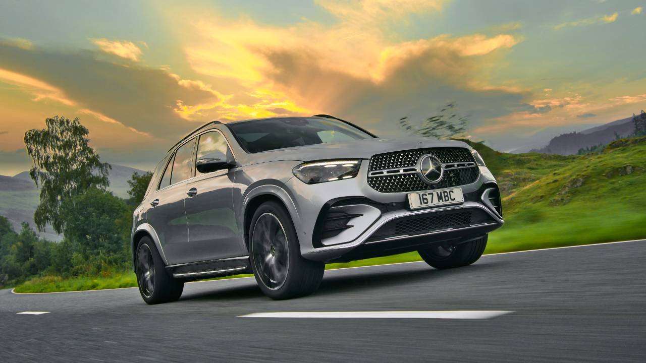Mercedes‑Benz GLE SUV driving along a winding road at sunset