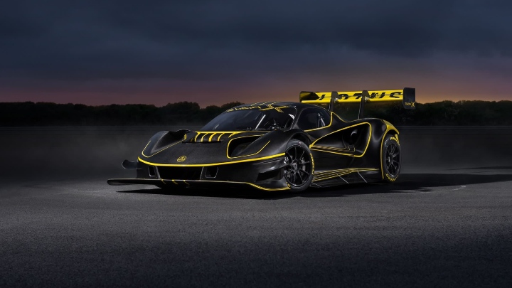Lotus Evija X electric hypercar front three-quarter view with black and gold livery at sunset track setting
