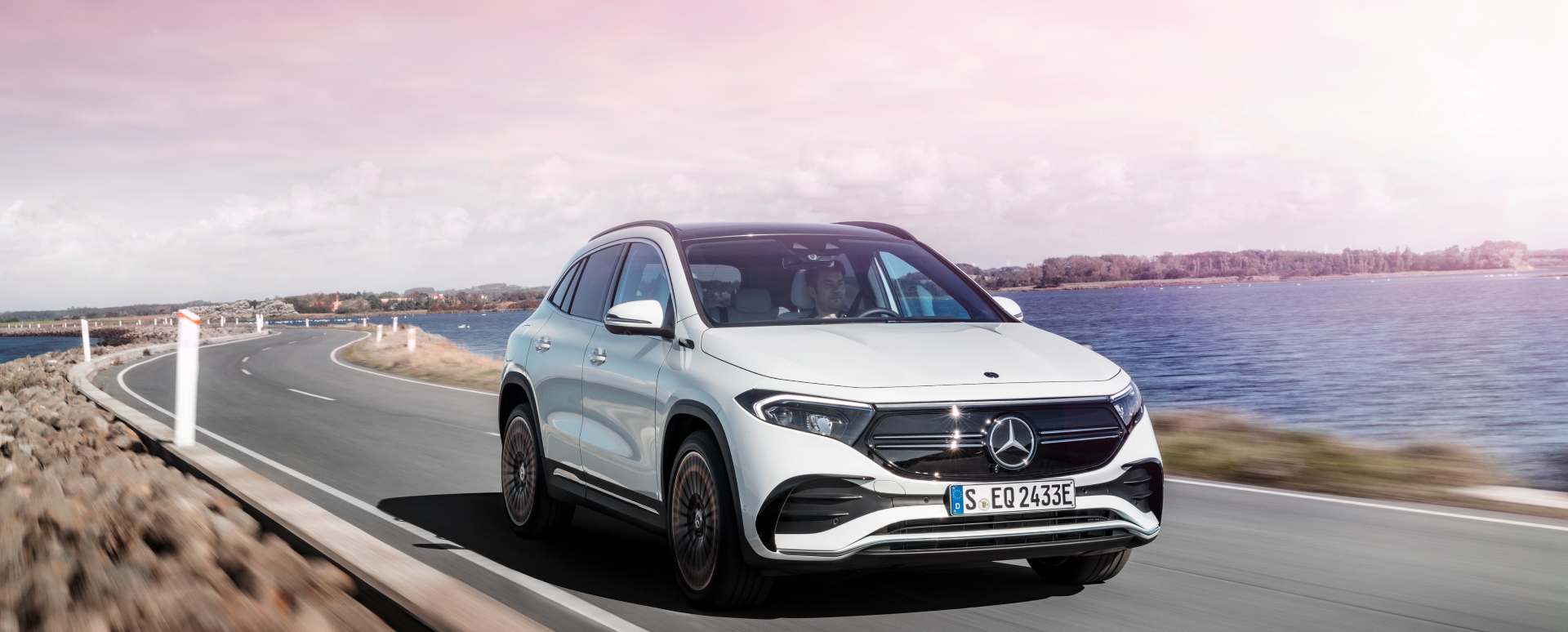 White Mercedes-Benz EQA driving on coastal road