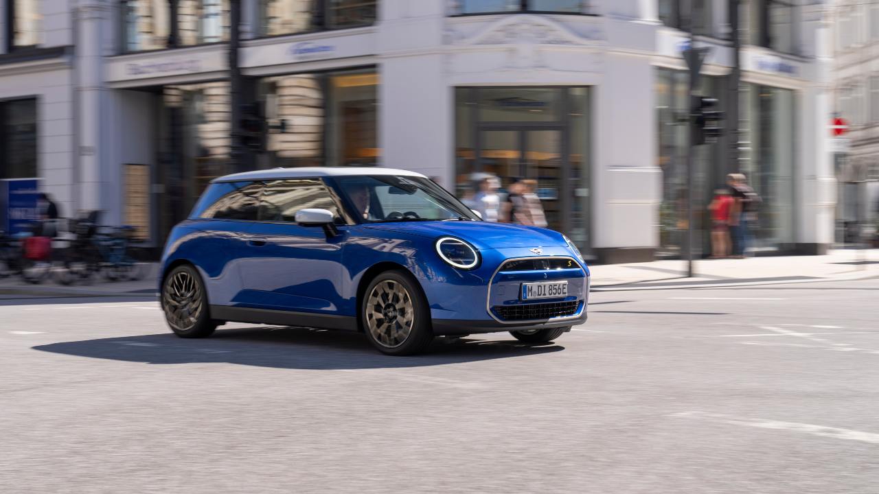 Blue Mini Cooper electric driving around corner in city