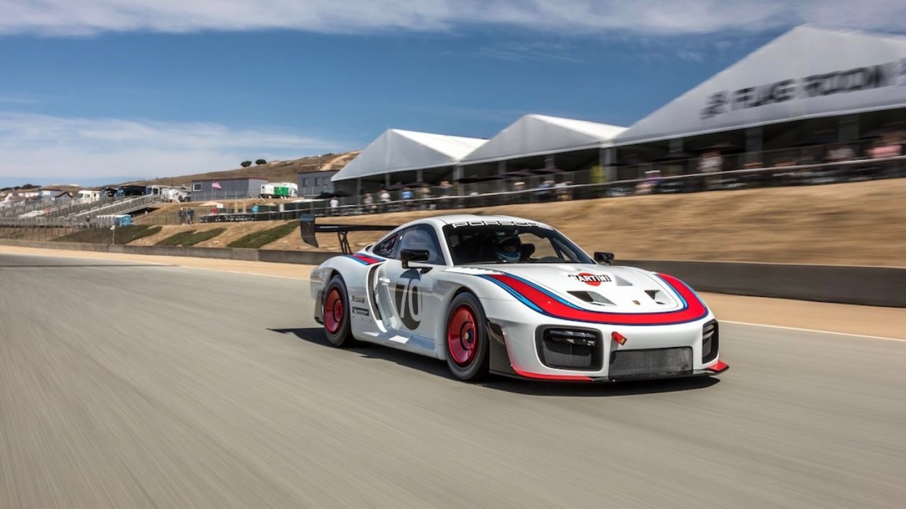 Porsche 935 race car with Martini livery driving at speed on racetrack, side three-quarter view