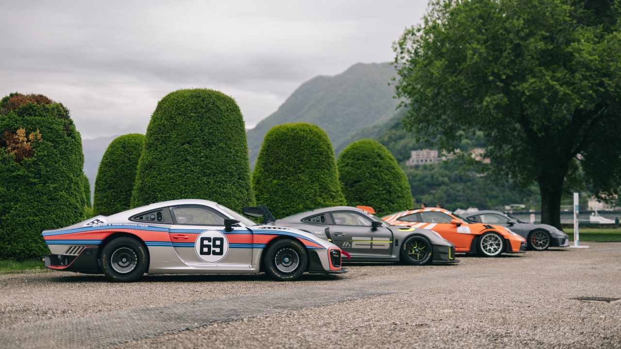 Porsche motorsport lineup including 935 and GT race cars parked outdoors with scenic backdrop