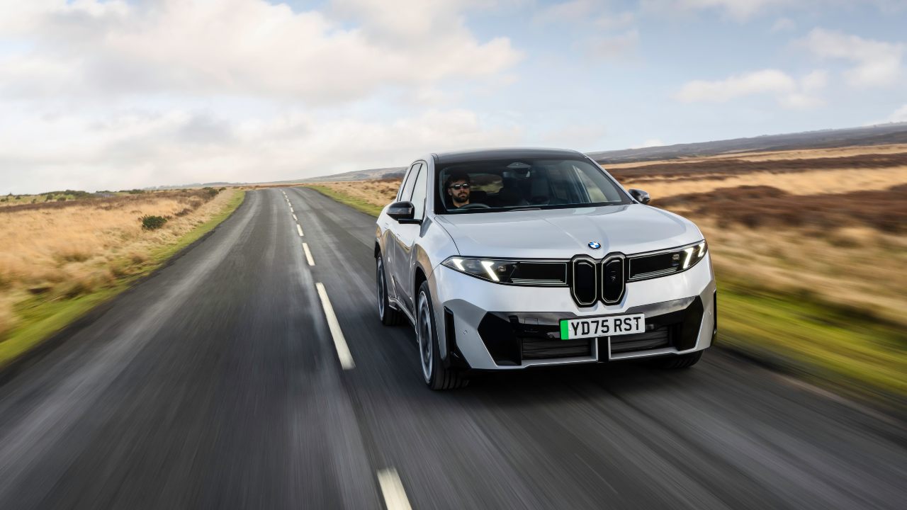 Front view of a grey BMW iX3 driving along an open country road