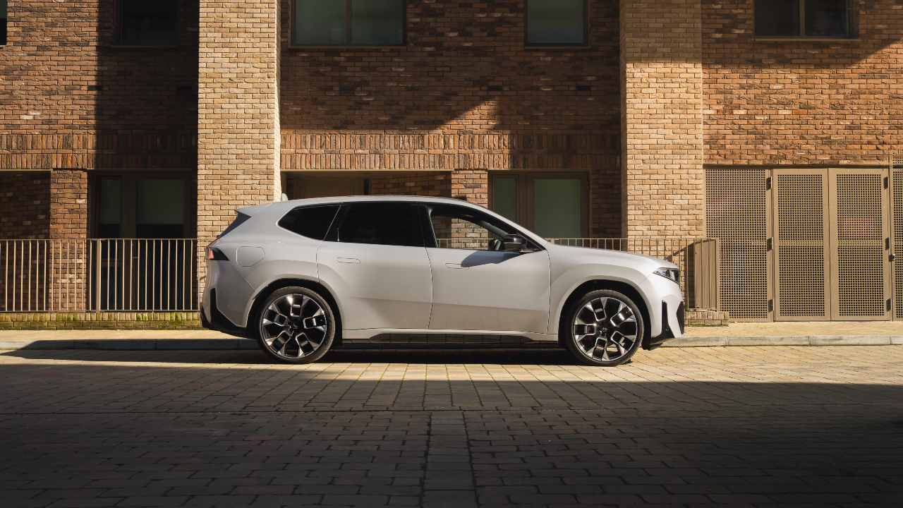 Side profile of a grey BMW iX3 parked in front of a modern brick building