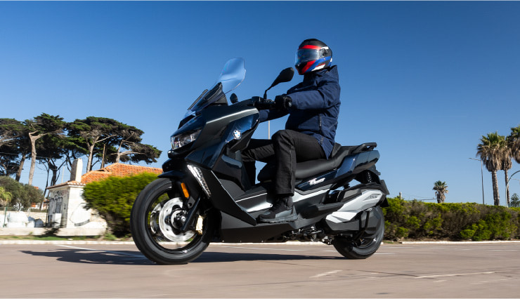Motorcyclist Riding BMW Motorrad CE 400 GT Through Town