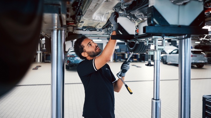 BMW Technician Underneath Car on Service Ramp