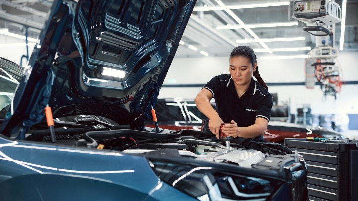 Female BMW Technician Working on Open BMW Engine Bay