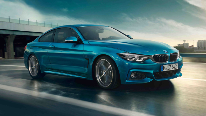 BMW 4 Series Coupe in blue driving on the road.