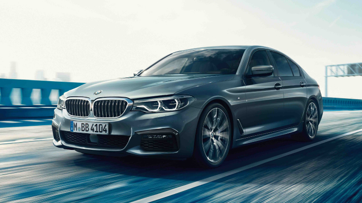 BMW 5 Series Saloon driving on the road.