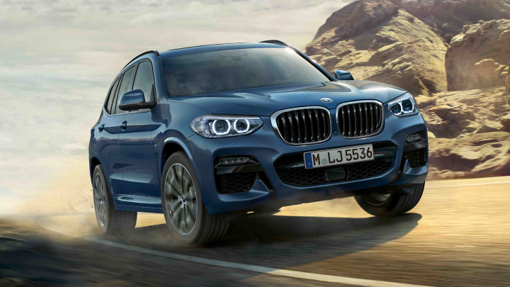 BMW X3 in blue driving on the road.
