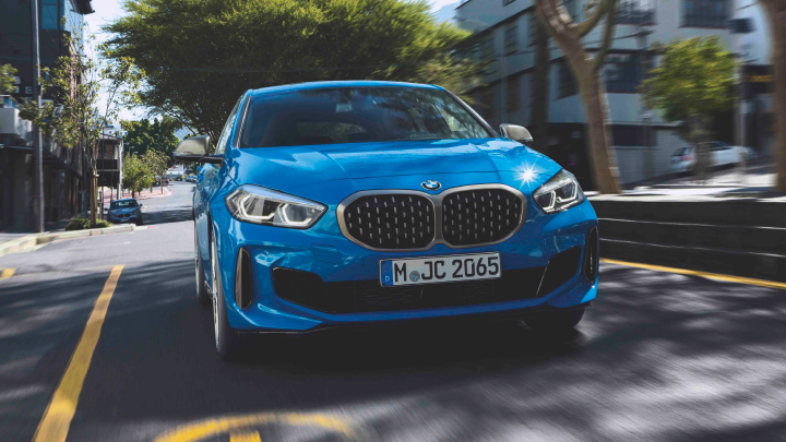 BMW 1 Series in blue driving on the road.