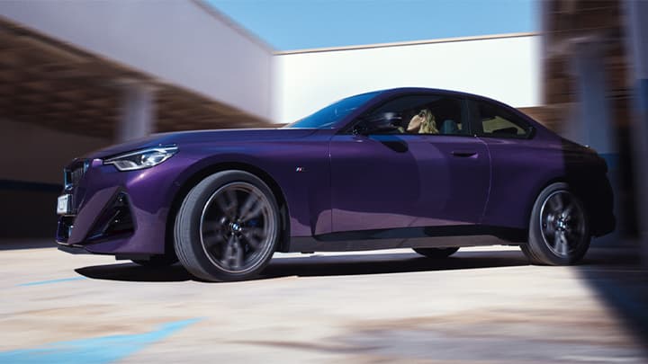 Front quarter shot of a driving purple BMW 2 Series Coupe